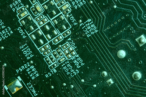 A close up macro photo of a generic technology motherboard circuit board  pcb  light with a green flash gel on a diagonal angle