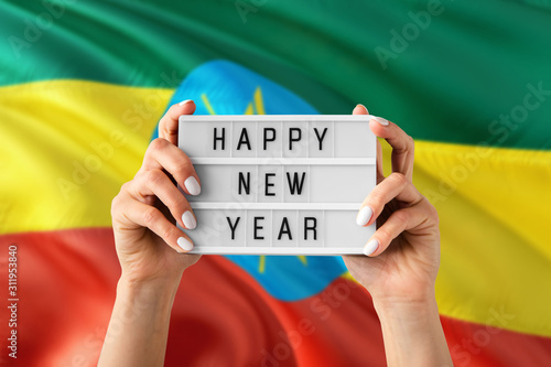 Ethiopia New Year concept. Woman holding Happy New Year sign with hands on national flag background. Celebration theme.