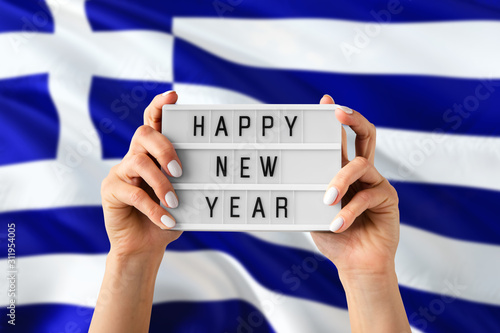 Greece New Year concept. Woman holding Happy New Year sign with hands on national flag background. Celebration theme.