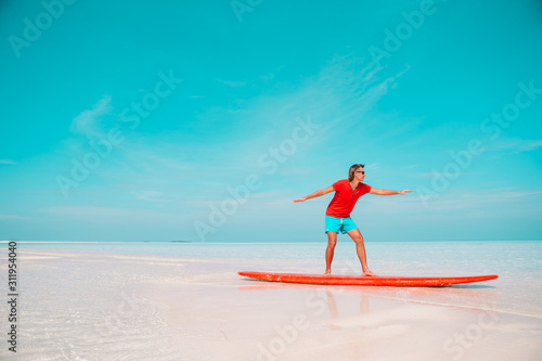 Happy young surf man on red surfboard at the sea © travnikovstudio