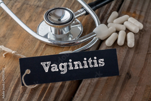 Vaginitis written on label tag with pills and Stethoscope on wood background