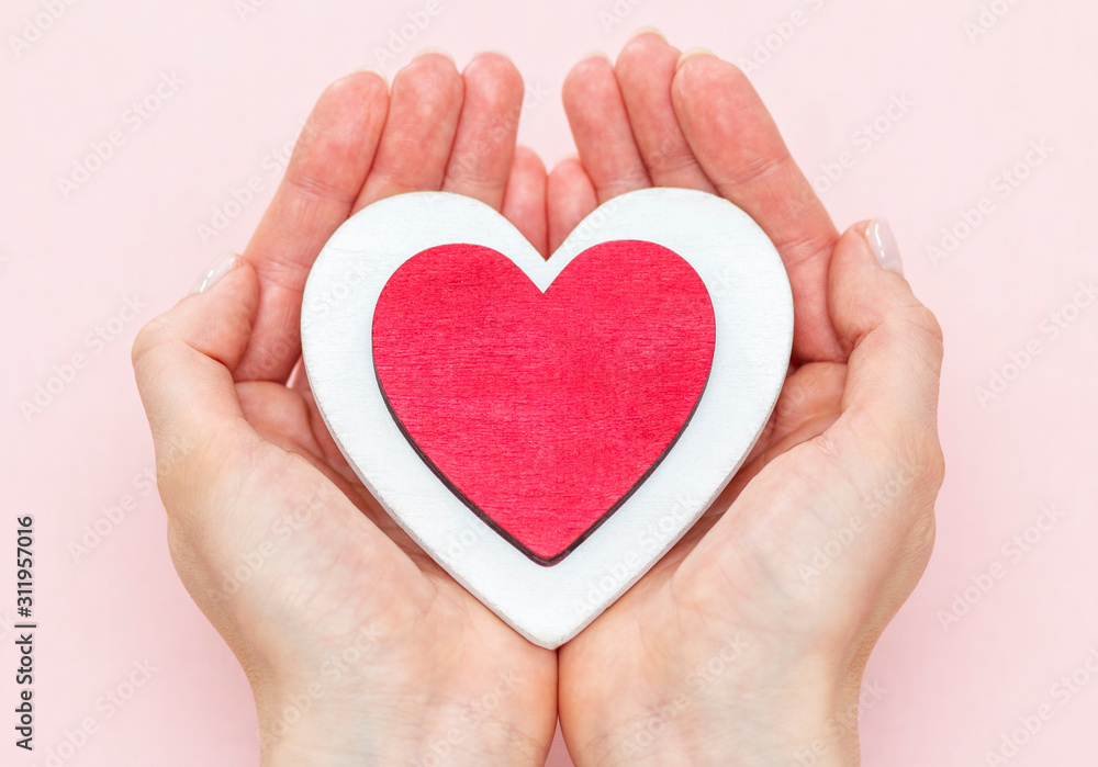man holds a red heart in his palms on a pink background man holds a red heart in his palms on a pink background