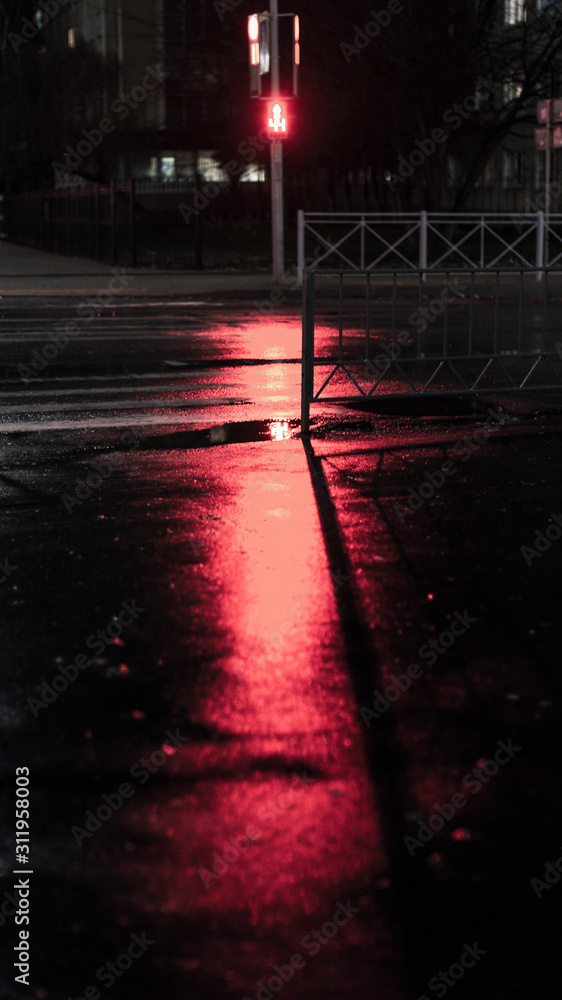 Reflection of traffic lights in puddles on the street of a night city.