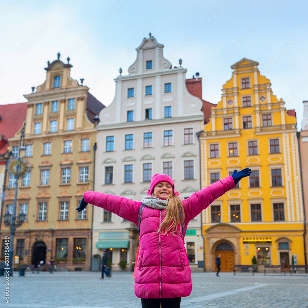 Portrait happy winter mood of joyful teen girl in pink jacket and hat having fun on square in trip on holidays . Positivity, joy, happiness, tourism, travel, vacation, freedom, trip