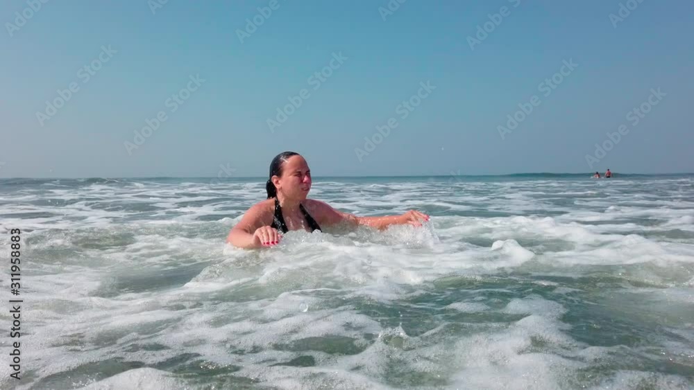 Woman waiting for sea wave. Side view of wet female swimming in sea water and waiting for foamy wave while resting on resort on sunny day Woman waiting for sea wave. Side view of wet female swimming in sea water and waiting for foamy wave while resting on resort on sunny day