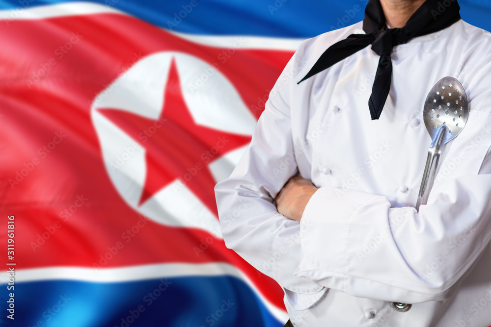 Fototapeta premium North Korea domestic food concept. Professional chef in white uniform is standing with metal spatula. Copy space for text.