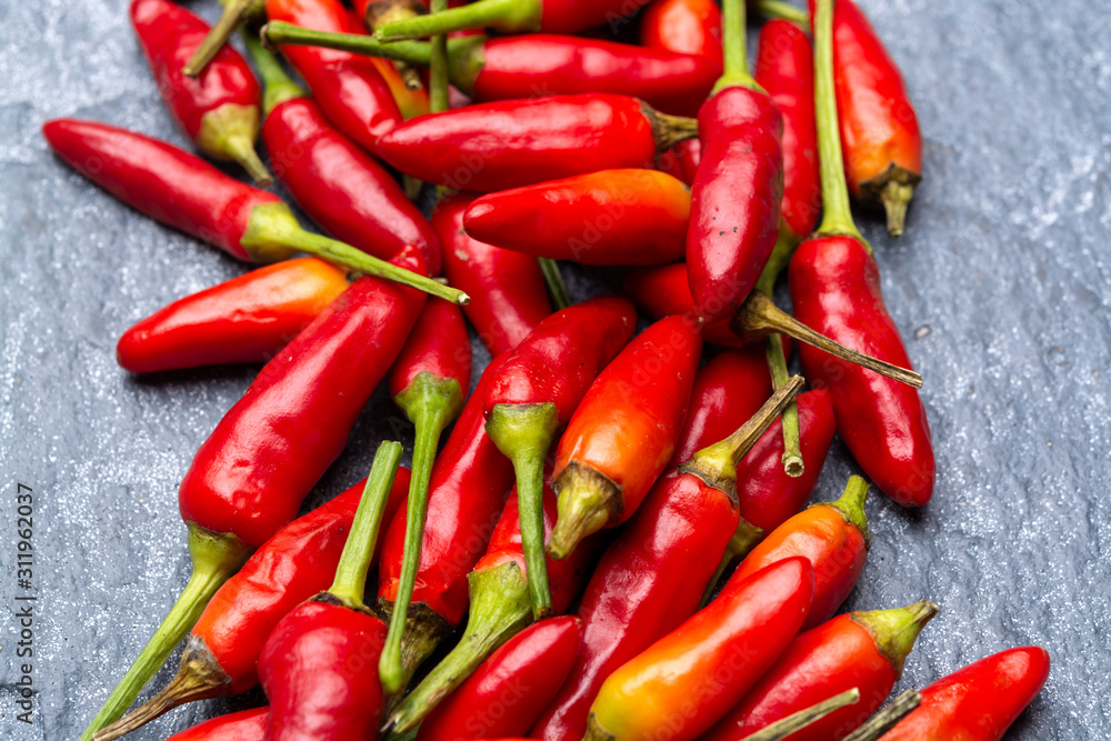 Fresh small red hot chili peppers on grey background