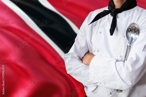 Trinidad And Tobago domestic food concept. Professional chef in white uniform is standing with metal spatula. Copy space for text.