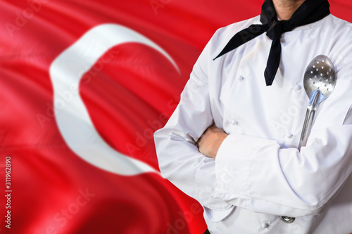 Turkey domestic food concept. Professional chef in white uniform is standing with metal spatula. Copy space for text.
