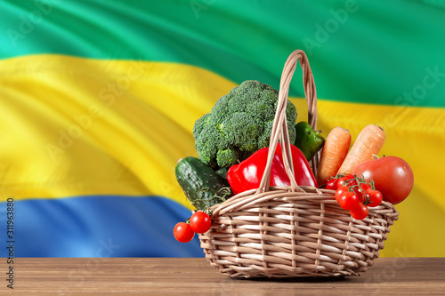 Gabon organic food concept. National flag background with basket full of vegetables on wooden table. Copy space for text.