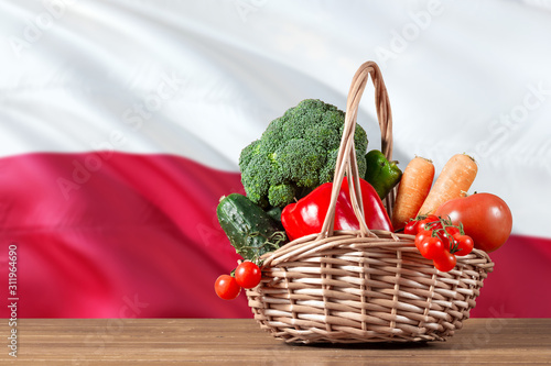 Poland organic food concept. National flag background with basket full of vegetables on wooden table. Copy space for text.