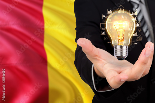 Guinea creativity concept. Businessman with a light bulb in his hand on national background. Innovation and technology theme.