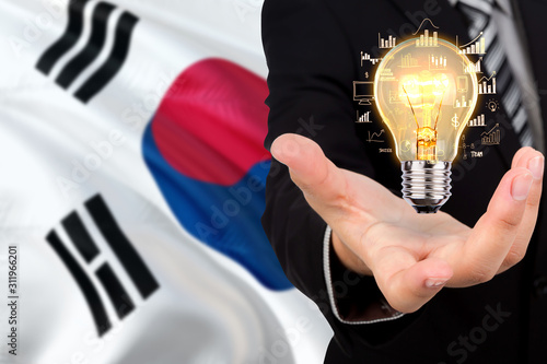 South Korea creativity concept. Businessman with a light bulb in his hand on national background. Innovation and technology theme.