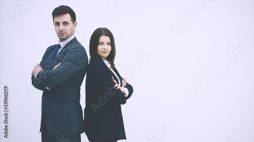 Business man and woman standing alongside, looking, folding their hands, giving thumbs up, nodding, smiling.