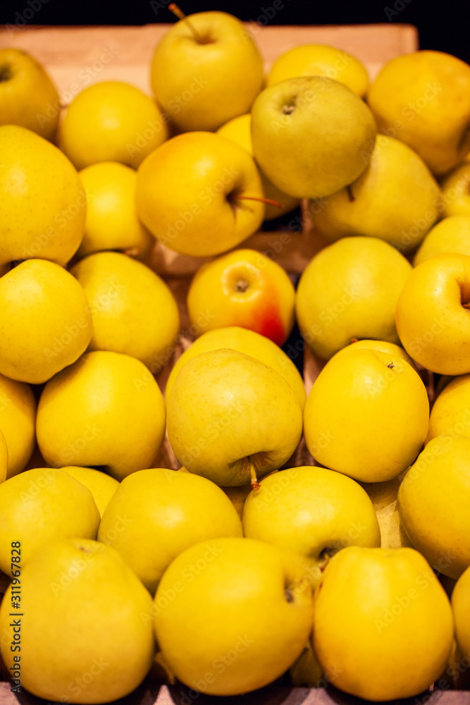 Yellow apples at market store background. Vertical photo 
