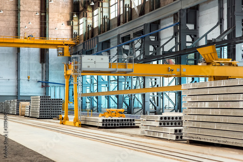 industrial premises of a plant for the production of floor slabs stacked in a pile in a workshop with automated equipment and an overhead crane.