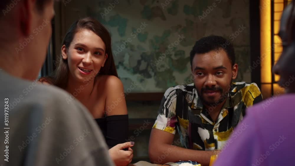 Multicultural men and women sit at lunch and girl tells a story Multicultural men and women sit at lunch and girl tells a story