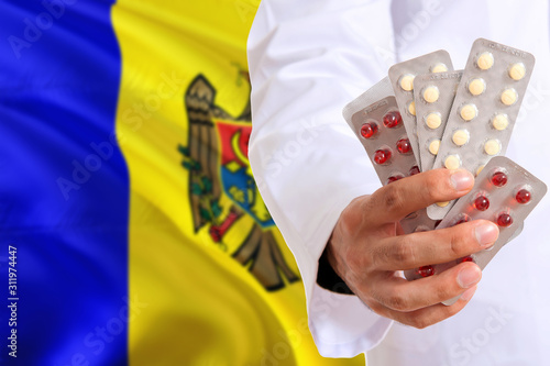 Moldova pharmacy and medicine concept. Doctor holding pills tablet on national flag background. Health theme with copy space for text.