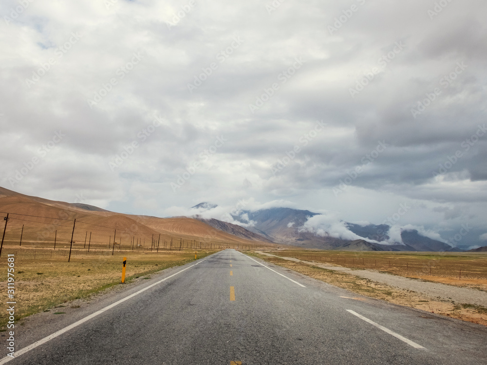 Empty highway passing through stormy mountain landscape