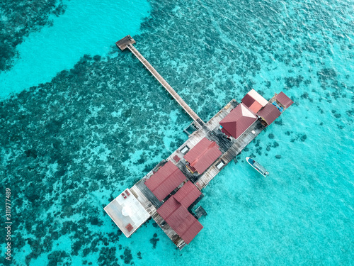 Aerial view of a tropical island in turquoise water. Luxurious over water villas on tropical island resort.