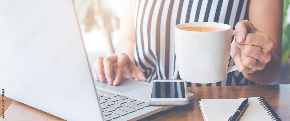 Business woman working at a laptop computer and her hand holding a cup of coffee. Business woman working at a laptop computer and her hand holding a cup of coffee.
