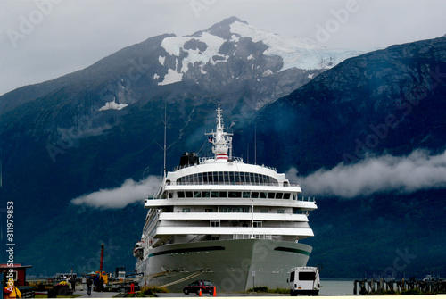 A cruise ship comes into an Alaskan port with snow and glaciers in the background.  © Guntherize