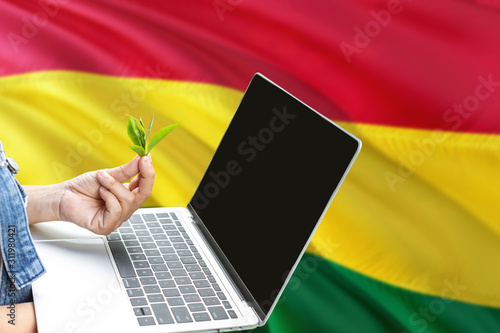 Bolivia modern agriculture concept. Farmers holding laptop  check tea on national flag background. Ecology theme with copy space.