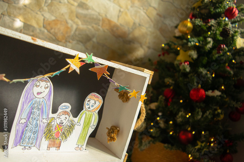 Child-made manger next to the christmas tree: christianity