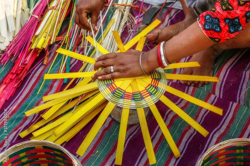 Woman hands tying a basket with strands of bamboo cane at a rural village in West Bengal
