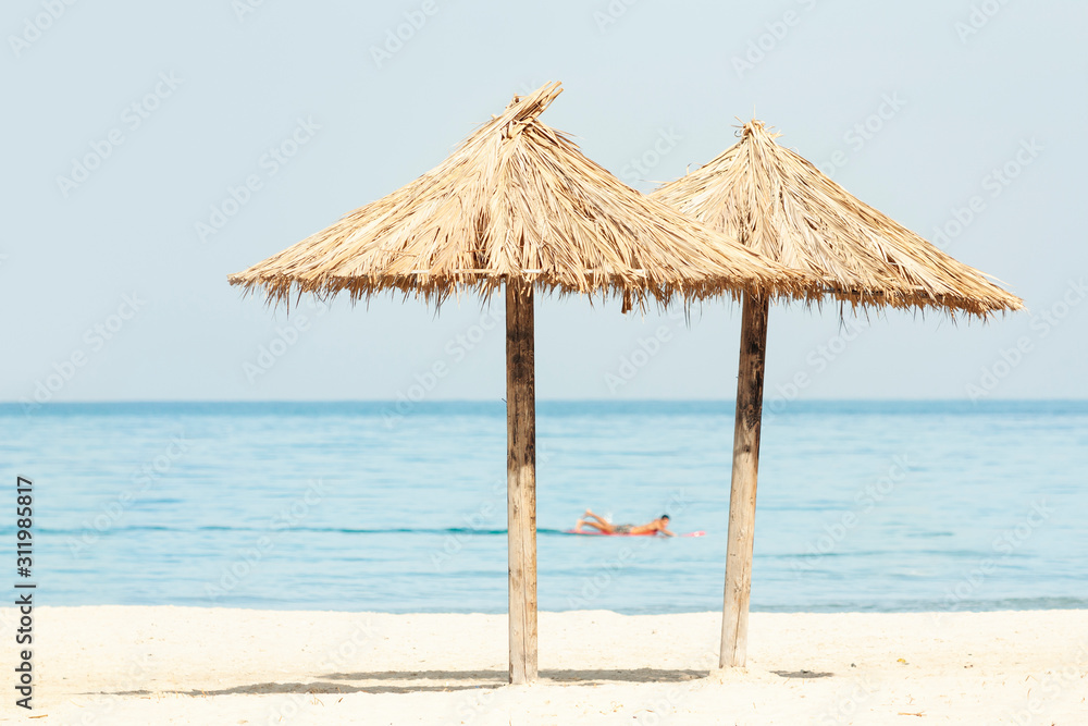 Two tropical beach parasols facing the sea