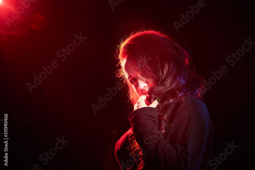 Portrait of chubby teen girl illuminated by red light and black background