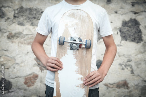 Caucasian boy with skateboard in his hands.