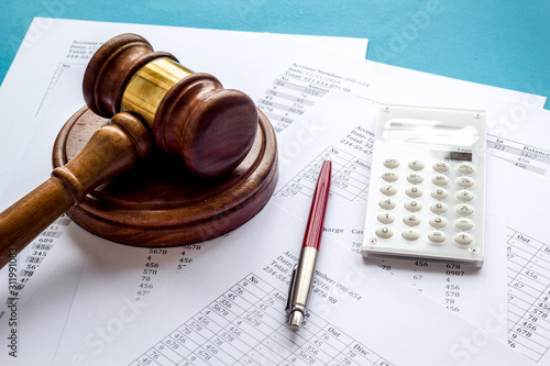 Taxes debt concept. Judge hammer near financial documents on blue background