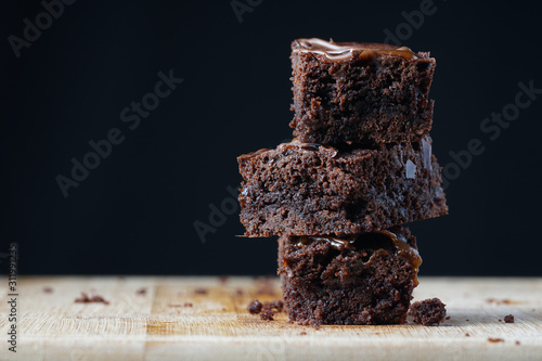 A stack of chocolate brownies on a wooden background. Home made bakery and dessert.