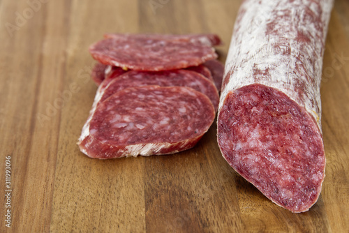 Close-up traditional sliced meat sausage salami on wooden board.