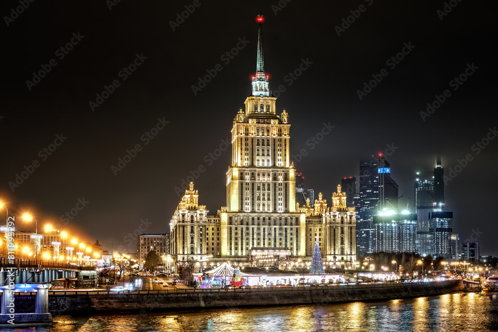 scenic moscow city russia architecture cityscape downtown landmark at night against dark sky background. Street wide side view of town skyline with old hotel tower at front of modern skyscrapers