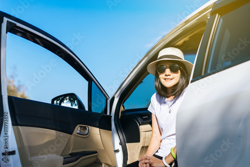 Traveller asian woman wearing hat and sunglasses sitting in car