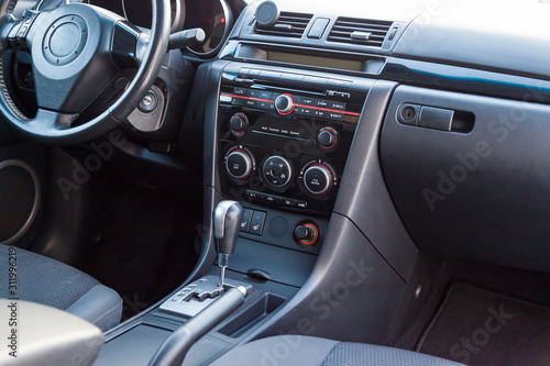 Comfortable front seats inside the car: the driver and passenger, tied with genuine black leather, modern interior design, the steering wheel covered with black wood and a luxurious center console. © Aleksandr Kondratov