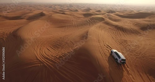 Aerial view of 4x4 off road land vehicle taking tourists on desert dune bashing safari in Dubai, UAE photo