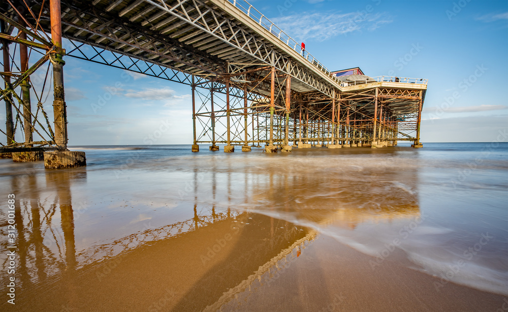Fototapeta premium Long exposure photo of a Victorian pier on a sandy beach