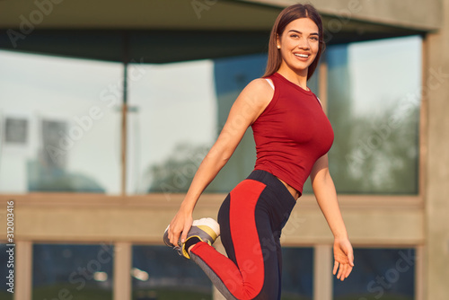 Young woman exercising   stretching in urban park.