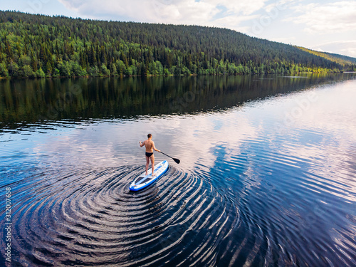 Man rowing oar on sup board blue sea water. Aerial top view paddleboard photo