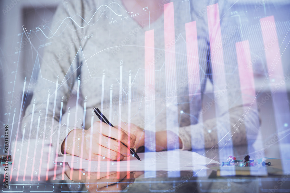 Hand taking notes in notepad. Forex chart holograms in front. Concept of research. Multi exposure Hand taking notes in notepad. Forex chart holograms in front. Concept of research. Multi exposure