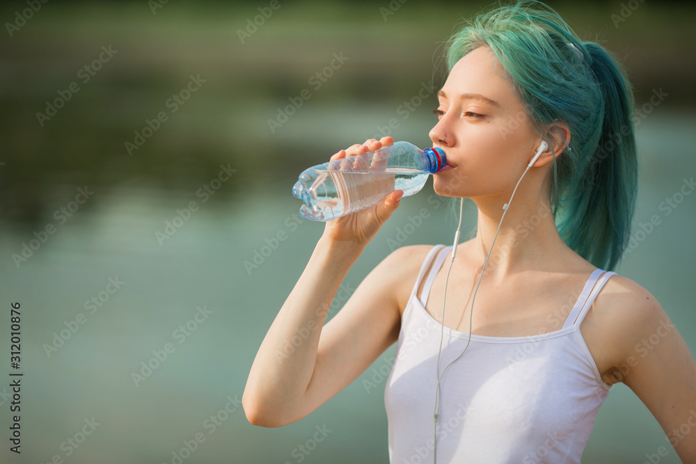 beautiful young woman in sportswear near a lake in summer with a bottle of water beautiful young woman in sportswear near a lake in summer with a bottle of water
