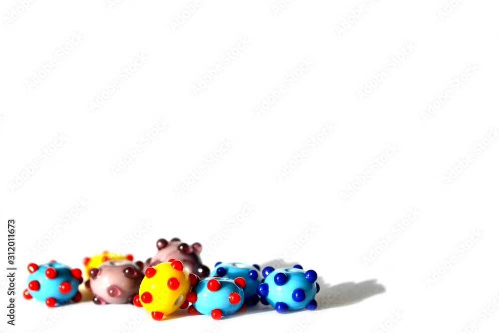 Obraz premium Beautiful colorful cheerful background made of handmade lampwork beads with dots. Beads are situated bottom left, isolated on white background. Suitable for text insert.