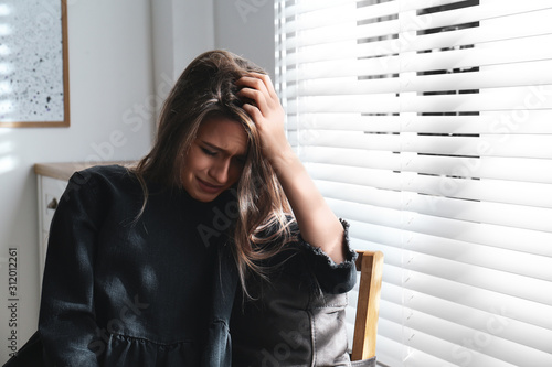 Fotografia Abused young woman crying indoors. Domestic violence concept