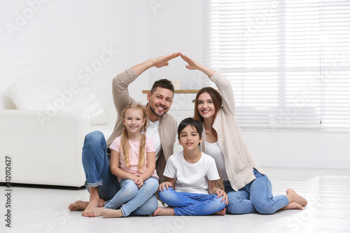 Happy family forming house roof with their hands at home. Insurance concept