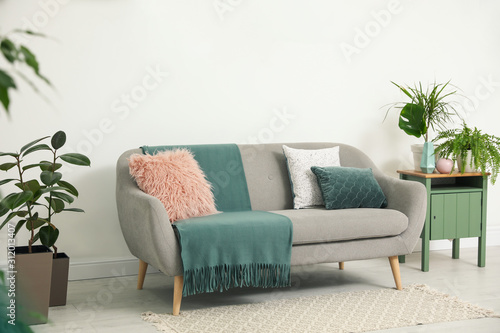 Soft pillows and plaid on grey sofa in living room
