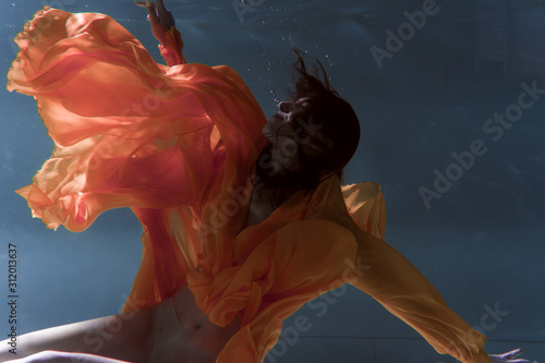 Fototapeta Naklejka Na Ścianę i Meble -  Beautiful girl swims underwater in a yellow dress. 2020 New Year trend Aqua Mente and fatom blue and lush lava. Underwater girl mermaid. Model suitable for advertising