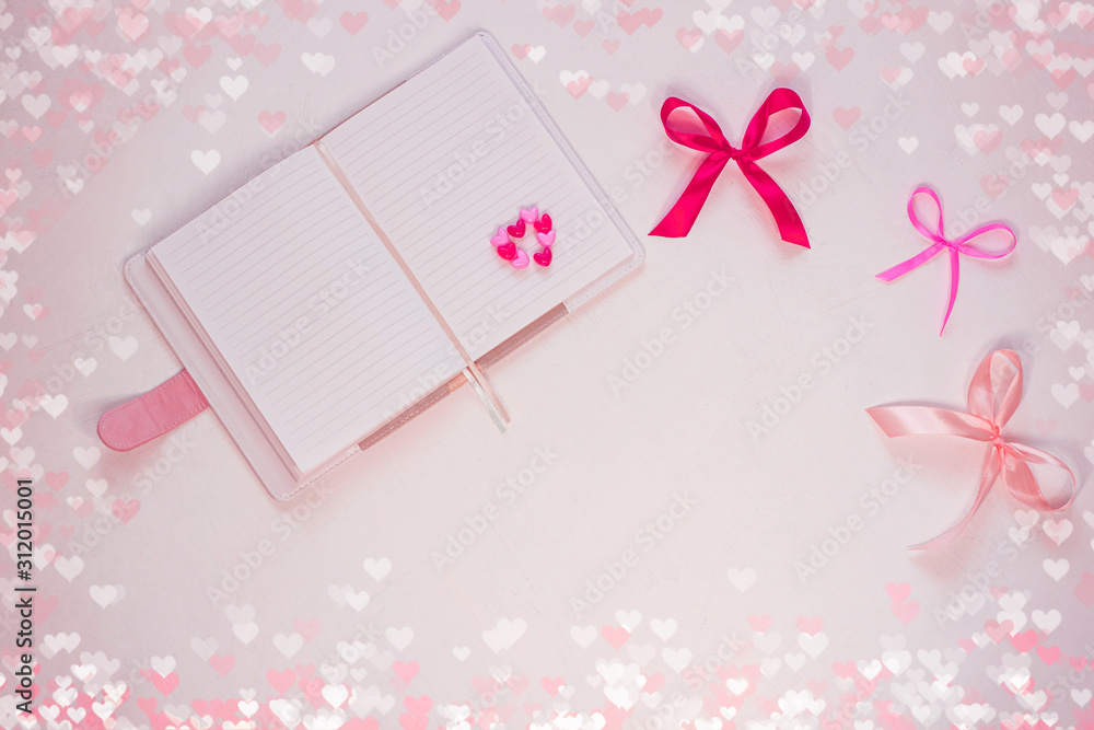 Valentines day flatlay. Blank diary, pink heartshaped beads, hearts and purple ribbon bow on white background. Notebook mockup,cute bokeh lights. Space for wishes text, sign. Lovers day,8 march banner